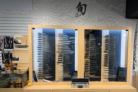 Japanese kitchen knives displayed in glass cases with wood handles and stainless steel blades
