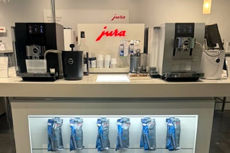 Jura automatic coffee machines displayed on a retail counter with accessories below